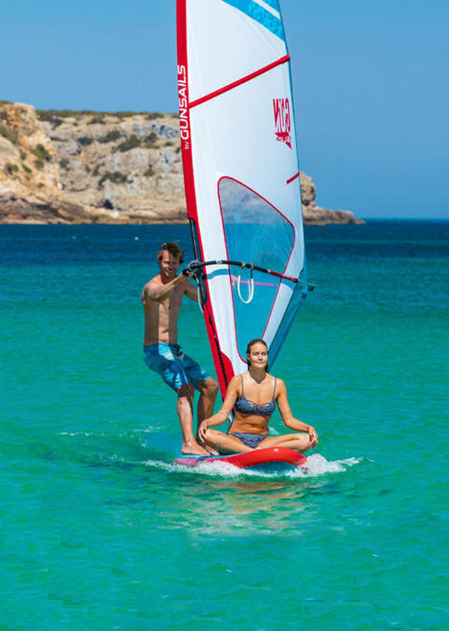 mise en situation de la planche à voile en mer avec deux personnes dessus une debout une en tailleur 